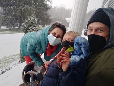 Dr. Melissa Houser (left) poses for a photo with Isaac Bernstein and his father, Matthew Bernstein outside on a snowy day. All three smile behind masks that cover their noses, mouths, and chins and Isaac.