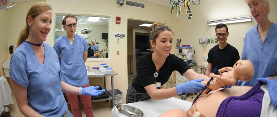 Racquel DeCastro ‘21 delivers her first “baby” in the UVM Clinical Simulation Lab flanked by classmates, sim lab staff, and associate OB/GYN clerkship director Erin Morris, M.D., at left