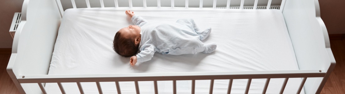 infant sleeping on back in empty crib
