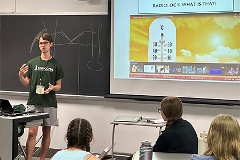 Larner medical student Eli Zettler ’27, AHEC scholar, mentors students at the Governor’s Institutes of VT Health and Medicine Summer Institute A male teacher standing in front of a class with the backs of three female students