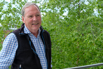 a man smiling against a backdrop of green leaves