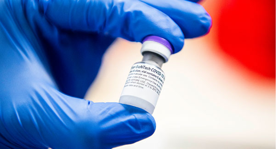 A UVM Medical Center staff member holds a vial of the Pfizer-BioNTech COVID-19 vaccine in a gloved-hand