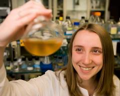 Smiling Student in Lab looking at a flask