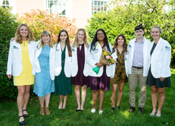 Students in white coats outside with flowers